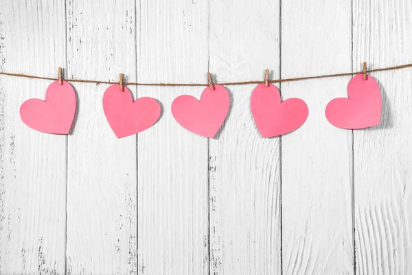 Wit geschilderde houten achtergrond met een slinger van roze harten. Natuurlijk touw en wasknijpers. Concept van erkenning van liefde, romantische relaties, Valentijnsdag in grunge stijl. Kopieerruimte — Stockfoto