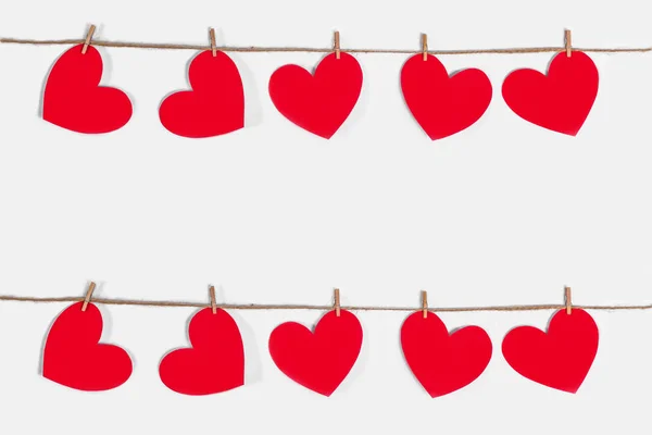 Guirnalda de corazones rojos sobre un fondo blanco aislado. Cuerda natural y pinzas de ropa. El concepto de reconocimiento en el amor, las relaciones románticas, Día de San Valentín. Copiar espacio — Foto de Stock