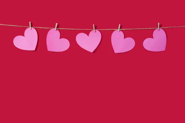 Garland of pink hearts on a red classic background. Natural rope and clothespins. Concept of Declaration of love, wedding, romantic relationship, Valentines Day. Copy space — 스톡 사진