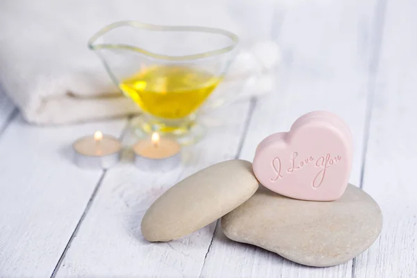 The concept of a Spa on Valentines Day. Candles, soap in the form of a heart with text I love you, stones, massage oil and a towel on a wooden background. Relaxation and wellness care. Bath procedure