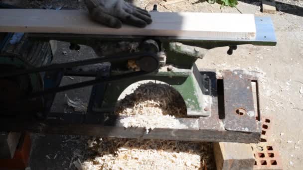 A man works on an old planing machine. Electric plane handles wooden boards in the home carpentry workshop. The workplace of a carpenter in the woodworking shop — Stock Video