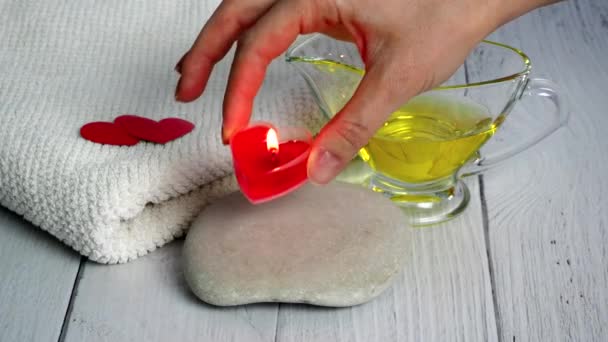 El concepto de un Spa el día de San Valentín. Una chica esteticista enciende velas en forma de corazón rojo. preparación de la oficina para sesiones de relajación y bienestar. Procedimiento de baño, cosmetología — Vídeos de Stock