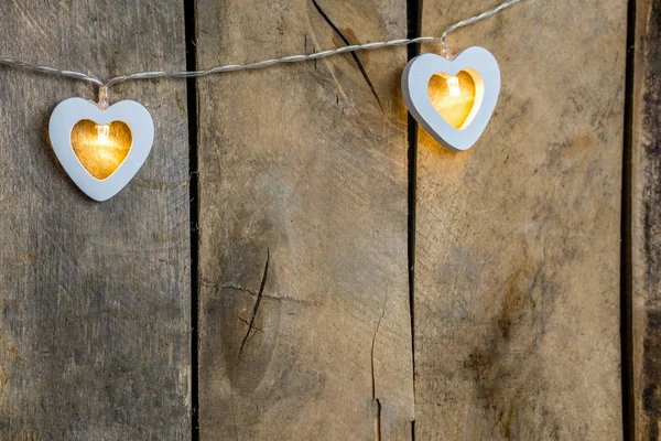 Old wooden background close-up with a garland of two white burning hearts. The concept of a Declaration of love, romantic relationships, Valentines day in grunge style. Copy space — 스톡 사진