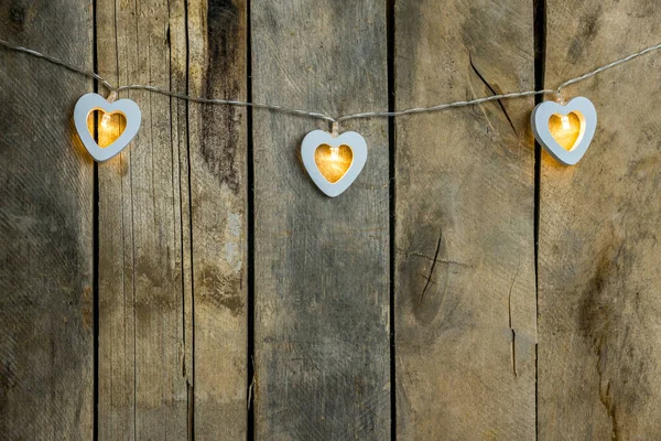 Oude houten achtergrond close-up met een slinger van twee witte brandende harten. Het concept van een liefdesverklaring, romantische relaties, Valentijnsdag in grunge stijl. Kopieerruimte. — Stockfoto