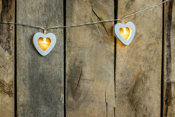 Old wooden background close-up with a garland of two white burning hearts. The concept of a Declaration of love, romantic relationships, Valentines day in grunge style. Copy space. — Stock Photo, Image