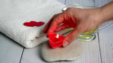 Sevgililer Günü 'nde Spa konsepti. Güzellik uzmanı bir kız kırmızı kalp şeklinde mumlar yakar. Rahatlama ve Sağlık oturumları için ofis hazırlığı. Banyo prosedürü, kozmetoloji