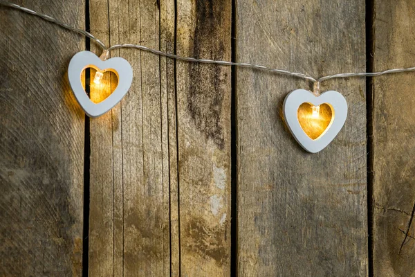 Old wooden background close-up with a garland of two white burning hearts. The concept of a Declaration of love, romantic relationships, Valentines day in grunge style. Copy space. — 스톡 사진