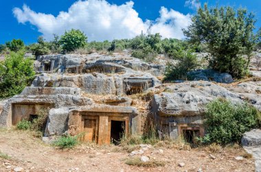 Türkiye 'nin Limyra ilindeki antik mezarlık. Kayadaki eski beton mezarın girişi. Mimarinin tarihi anıtına bir gezi. Ataların gökyüzüne daha yakın gömülmesi..