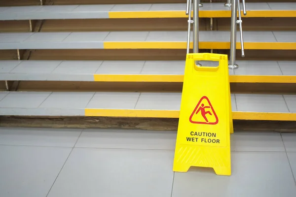 Sign showing warning of caution wet floor. Sign near the steps in an office or entertainment Mall. Cleaning of ceramic tiles in a store. Copy space. — Stock Photo, Image