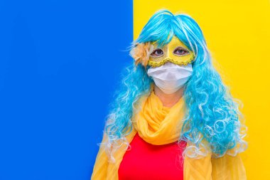 Venedik karnavalında Coronavirus 'a karşı koruma kavramı. Mavi peruklu ve sarı karnaval maskeli, bayramı kutlayan Virüs tacından bir sağlık maskesi takan zeki bir kadın. Boşluğu kopyala.