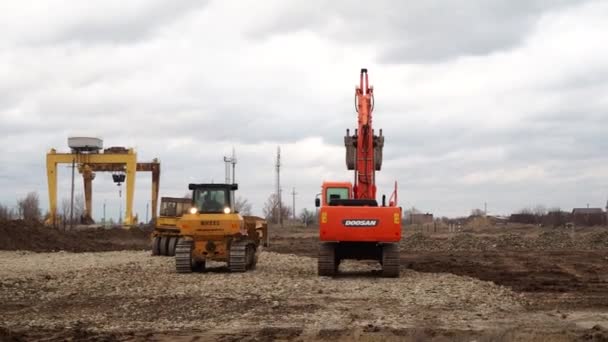 建設現場でのクローラーローダーショベル、ブルドーザーやローラー作業。機械は掘削作業を行う。住宅用の土壌や瓦礫の圧縮。ロシアのヴォルゴンドスク2020年3月10日. — ストック動画