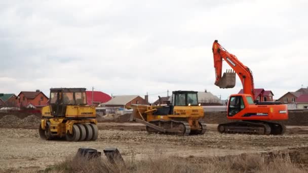 Excavadora de cargador de orugas, excavadora y trabajos de rodillos en el sitio de construcción. Las máquinas realizan trabajos de excavación. Compactación de suelos y escombros para edificios residenciales. Volgodonsk, Rusia 10 marzo 2020. — Vídeos de Stock