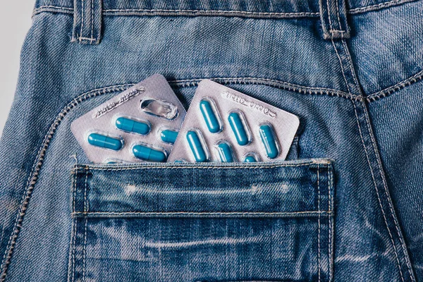 Dois pacotes de cápsulas azuis no bolso de suas pantas.Comprimidos para a saúde dos homens e energia sexual em jeans. Conceito de ereção, potência. Tratamento da infertilidade masculina, impotência e prostatite. — Fotografia de Stock