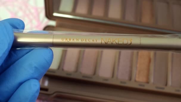 Presentation i butiken av den nya paletten av makeup skuggor nakna 3 från Urban Decay. Mjuk elastisk dubbelsidig borste närbild. Översyn av kosmetika för kvinnor. Volgodonsk, Ryssland-11 mars 2020. — Stockvideo