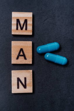 İki mavi kapsül ve yazıtçı adam. Siyah arka planda erkek sağlığı ve cinsel enerji hapları. Ereksiyon kavramı, iktidar. Erkeklerin kısırlık ve iktidarsızlık tedavisi.