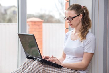 Ev karantinası. Uzaktan kumandalı iş. Koronavirüsten koruma. Camda gözlüklü, bilgisayarlı, beyaz bir kadın. Arkadaşları ve akrabalarıyla çevrimiçi iletişim kurmak. Boşluğu kopyala