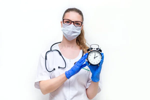ウイルスから身を守る時間だ 隔離室にいてコロナウイルスのパンデミックを防げ 白い隔離された背景に彼女の手の時計と医療保護マスクの女性医師 — ストック写真
