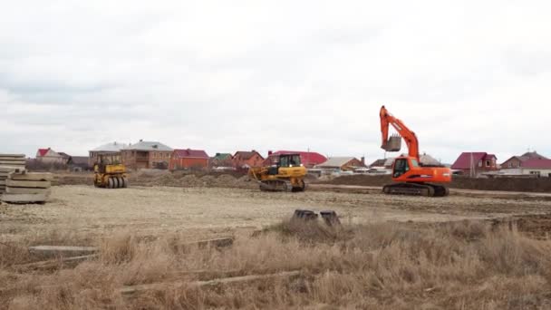 Excavadora de cargador de orugas, excavadora y trabajos de rodillos en el sitio de construcción. Las máquinas realizan trabajos de excavación. Compactación de suelos y escombros para edificios residenciales. Volgodonsk, Rusia 10 marzo 2020. — Vídeo de stock