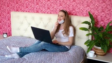Uzaktan kumandalı iş. Beyaz atlı güzel bir vlogger kızı laptopla tıbbi bir maskeyle odasından canlı yayın yapıyor. Sağlık hakkında konferans. Karantinada çevrimiçi kurslar ve e-eğitim.