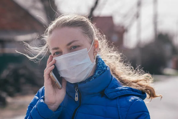 Menina caucasiana em licença médica em máscara protetora médica, chamadas ao telefone, chama um táxi. Epidemia de gripe sazonal e vírus frio. Proteção contra doenças respiratórias durante pandemias e epidemias — Fotografia de Stock