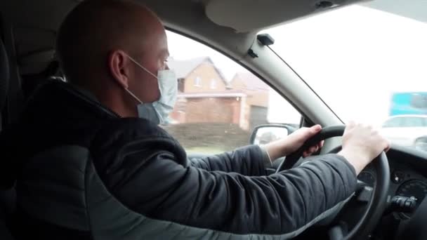 Un homme conduisant une voiture avec un masque médical de protection. Conduite en toute sécurité dans un taxi pendant un coronavirus pandémique. Protéger le conducteur et les passagers contre les bactéries et les virus en quarantaine . — Video