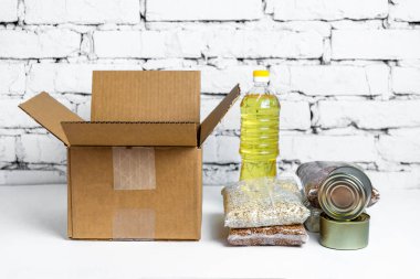 Beyaz arka planda karton bağış kutusundaki yiyecekler. Karantina süresi için gerekli malların kriz önleyici stoku. Yemek teslimatı, koronavirüs. Yiyecek kıtlığı.