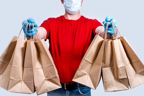 安全な配達だ 赤い制服と保護マスクと手袋の宅配便は 大規模な注文 多くの紙袋 検疫中の非接触配達食品を保持しています ボランティアの寄付 廃棄物ゼロ — ストック写真