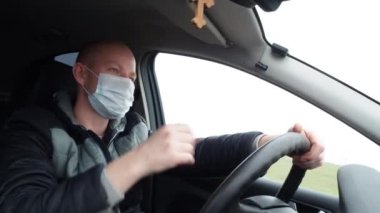 Koruyucu tıbbi maskeli bir adam araba kullanıyor. Salgın koronavirüs sırasında takside güvenli sürüş. Sürücüyü ve yolcuları karantinadaki bakteri ve virüs enfeksiyonundan koru.
