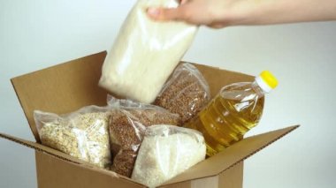 Karton bağış kutusunda yiyecek, beyaz arka planda izole edilmiş. Karantina süresi için gerekli malların kriz önleyici stoku. Yemek teslimatı, koronavirüs. Yiyecek kıtlığı. Metinle imzala.