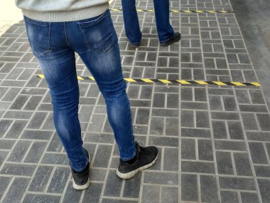 Caddede bir dükkan için kuyruğa gir. Sosyal mesafe. İnsanların ayakları yiyecek için güvenli bir şekilde mağazaya girmek için bekliyor. Koronavirüs salgını sırasında birbirinden uzak olmak için çizgilerin güvenli bir şekilde işaretlenmesi.