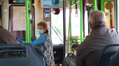 Koruyucu maskeli ve eldivenli bir kadın toplu taşıma araçlarına biniyor. Otobüs yolcuları koronavirüsten korunuyor. Salgın sırasında yaşam tarzı. Volgodonsk, Rusya-Mayıs 2020.
