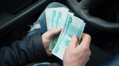 Bir adam para sayar. Erkeklerin elinde bir sürü ruble para var. Rus bir taksi şoförünün maaşı. Yeni bir araba alıyorum. Trafik kurallarını ihlal ettiği için bir trafik polisine rüşvet..