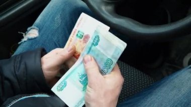 Bir adam para sayar. Erkeklerin elinde bir sürü ruble para var. Rus bir taksi şoförünün maaşı. Yeni bir araba alıyorum. Trafik kurallarını ihlal ettiği için bir trafik polisine rüşvet..