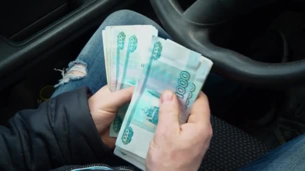 Um homem conta dinheiro. Muitas notas de rublo nas mãos dos homens. Salário de um taxista russo. A comprar um carro novo. Um suborno a um inspetor de polícia de trânsito por violar regras de trânsito . — Vídeo de Stock