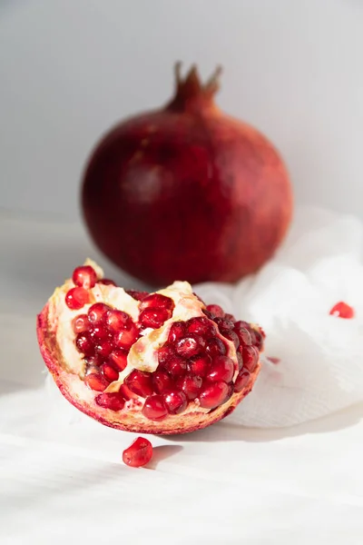 Ganze Früchte und die Hälfte eines reifen Granatapfels liegen auf einem Tisch auf einem hölzernen Untergrund. Bio-Früchte — Stockfoto