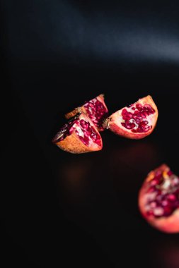 Siyah arka planda dört dilim nar yatar. Taze olgun meyve. Doku.
