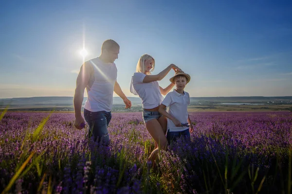 Família feliz em um campo de lavanda no pôr do sol . — Fotografia de Stock