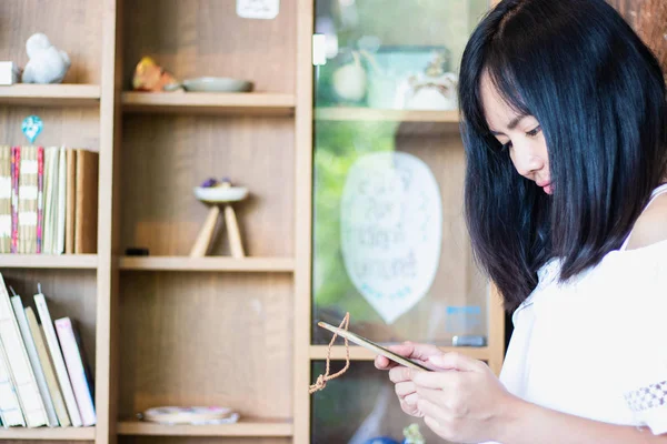 亚洲可爱的女孩在咖啡店读了一个交流板。 — 图库照片