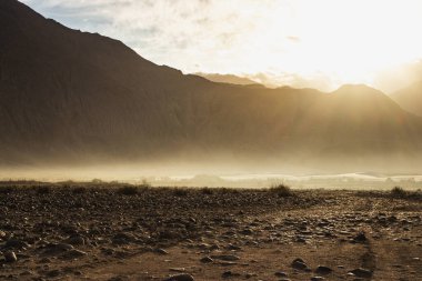 Hindistan 'ın Nubra Vadisi' nde, Leh Ladakh 'ta gündoğumu arka planında çarpıcı bir ışık ve güzel bir sis var. Lens alevli ışık manzarası.