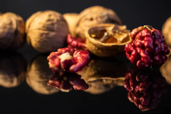 Koyu renkli bir masada pembe ceviz çekirdekleri. Siyah arkaplan