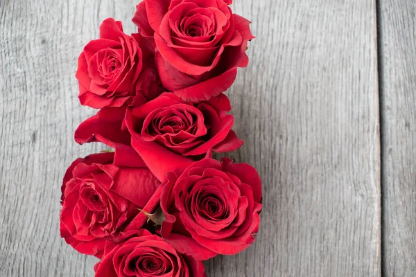 Kırsal bir arka planda kırmızı güller. Gri ahşap arka planda güller