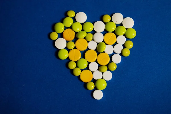 Mavi arka planda renkli haplar. Sarı, yeşil ve beyaz daireler kalbi oluşturur.
