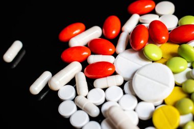 Siyah arka planda sarı, beyaz, yeşil ve kırmızı haplar