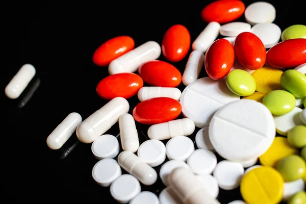 Siyah arka planda sarı, beyaz, yeşil ve kırmızı haplar