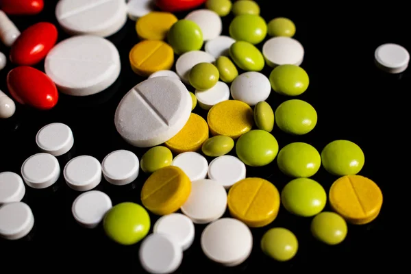 Siyah arka planda sarı, beyaz, kırmızı ve yeşil haplar