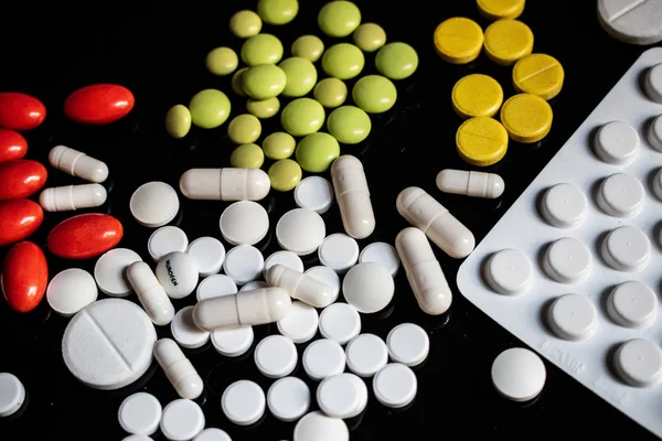 Siyah arka planda sarı, beyaz, yeşil ve kırmızı haplar