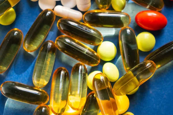 Mavi arka planda renk hapları ve şeffaf kapsül