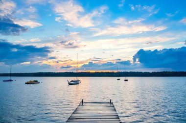 Yaz öğleden sonra manzarası. Ahşap iskele ve gün batımında denizde tekne..