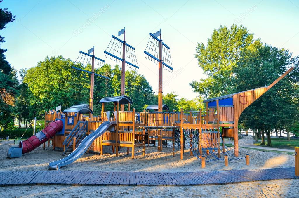 Beautiful playground for children on the lake. Wooden playground in the shape of a ship.