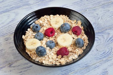 Sağlıklı, tatlı bir kahvaltı. Yabanmersinli yulaf ezmesi, ahududu ve muzlu.